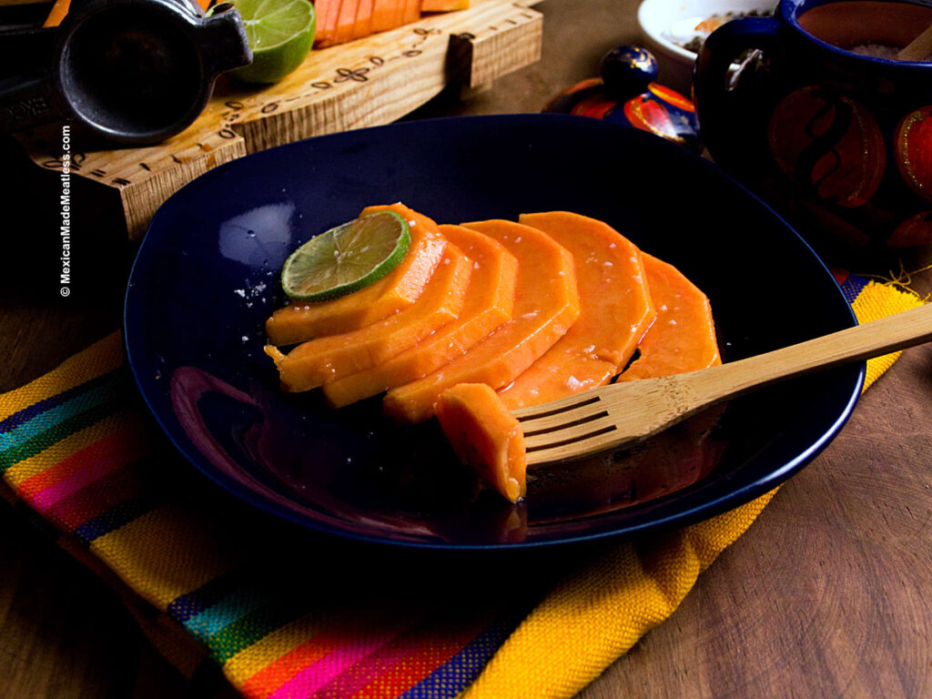Papaya slices drizzled with lime juice and a little salt on a blue plate.