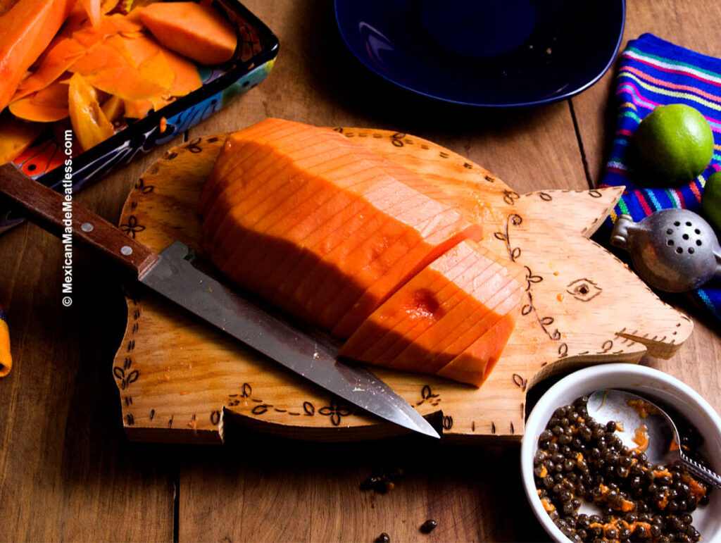 A sliced papaya on a cutting board ready to eat.
