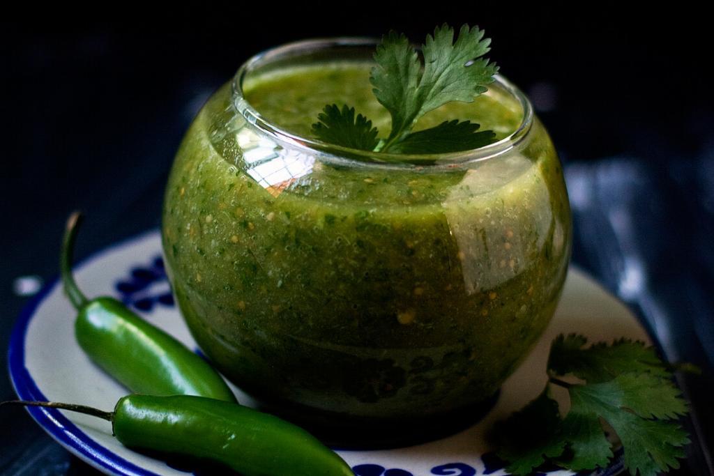 Small glass cup filled with homemade salsa verde inside. 