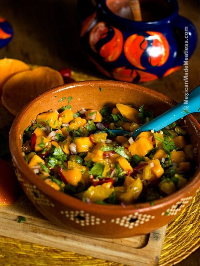 Mexican terracotta bowl filled with chunky mango pico de gallo salsa.