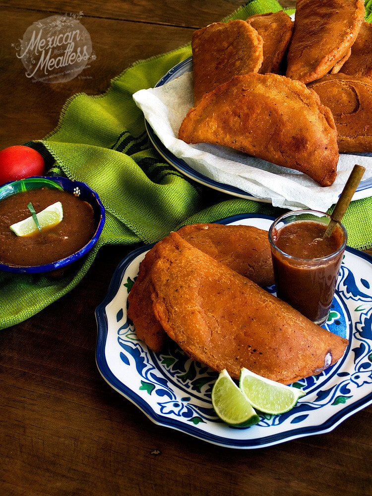 Black Bean and cheese empanadas with red salsa on a blue and white plate.