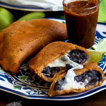 Black bean and Oaxaca cheese empanadas on a blue and white plate.
