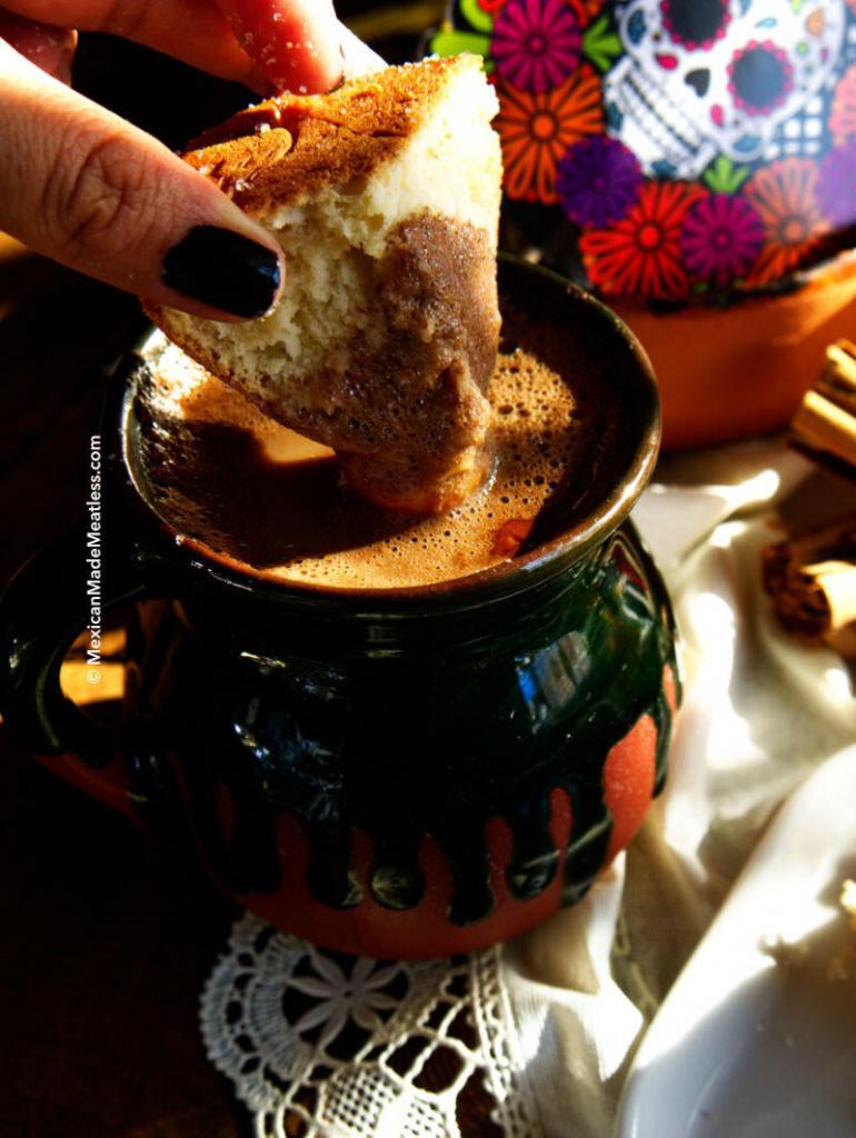Pan dulce being dipped into a cup of hot chocolate