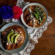 Two plates with vegan enfrijoladas, which are like enchiladas but with a creamy bean sauce.