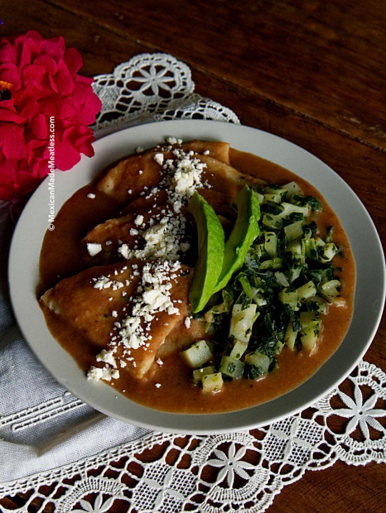 A plate of vegan enfrijoladas with vegetables and cheese.