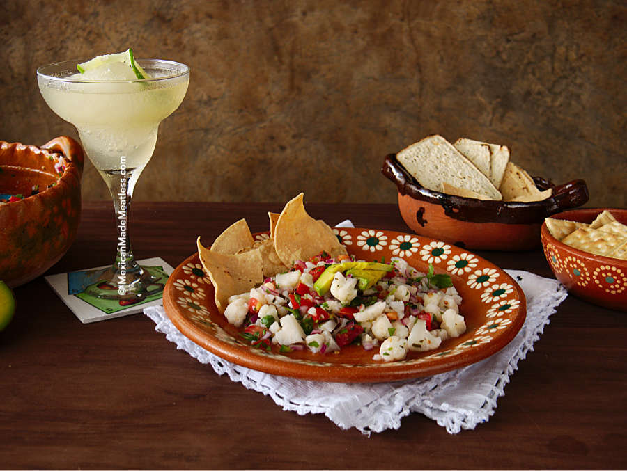 A plate of vegan cauliflower ceviche served with corn chips and an ice-cold classic margarita. 