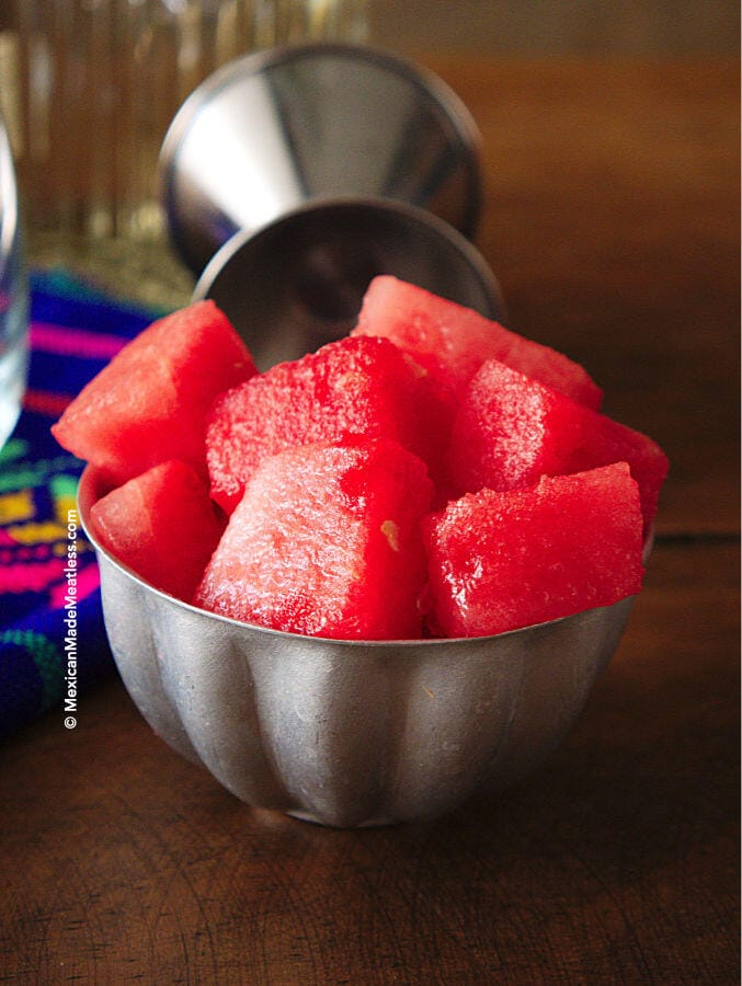 Chunks of freshly cut seedless watermelon in a small silver bowl.