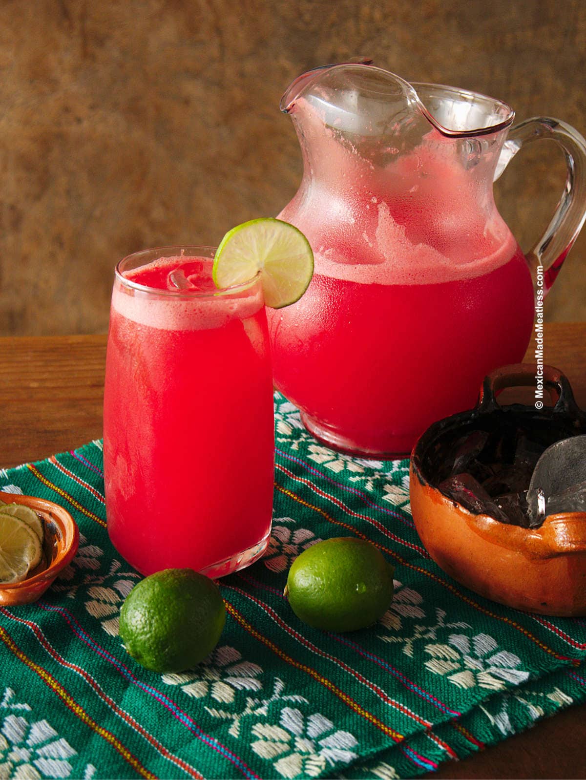 A pitcher and glass of ice cold watermelon agua fresca.