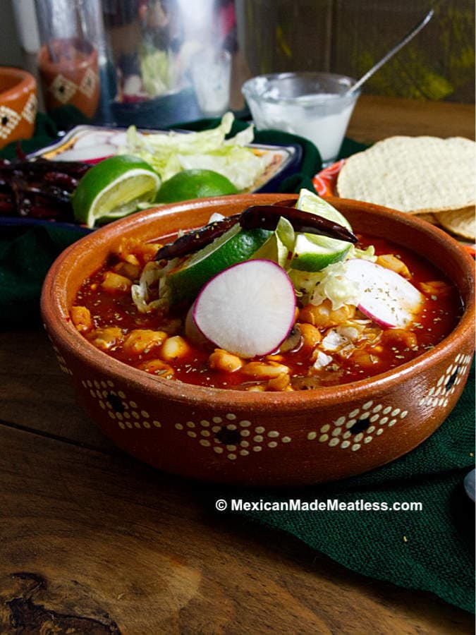 A bowl of Mexican red pozole with all of their delicious toppings.