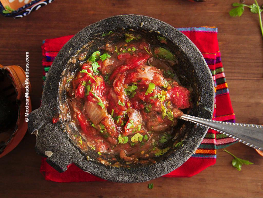Chunky roasted tomato salsa served inside a molcajete or stone mortar and pestle.