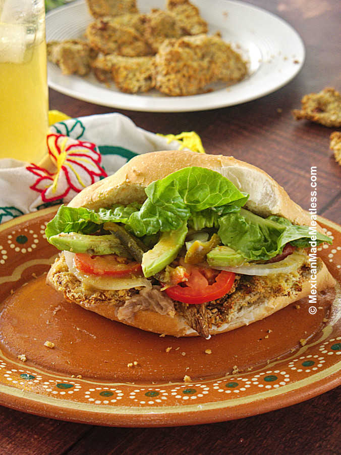 One Mexican torta de milanesa or chicken cutlet torta made vegan served on a brown plate. 
