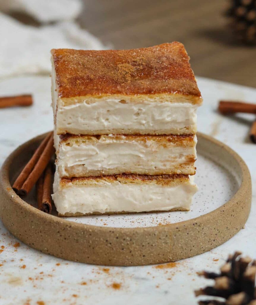 Three slices of vegan Churro Cheesecake stacked on top of each other.