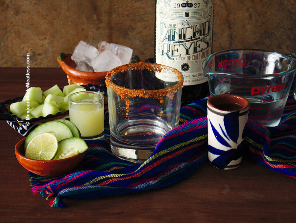 Ingredients for cocktail are Ancho Reyes chile liqueur, cucumbers, lime juice, chile and salt for rim and ice cubes.