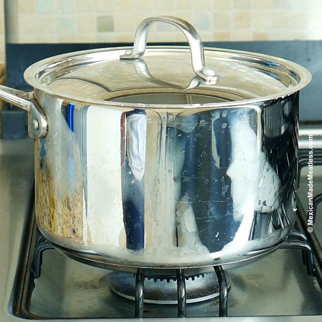 A large pot on the stove steaming tamales.
