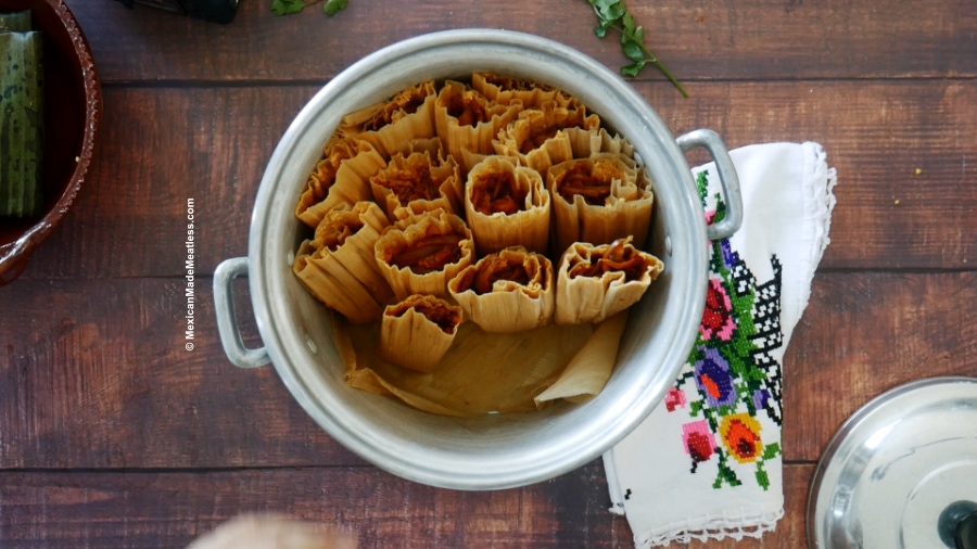 Vegan red chile tamales steaming inside Mexican steamer pot called a tamalera.