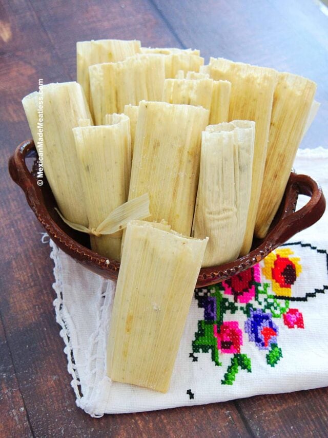A bunch of uncooked tamales inside a brown bowl and ready for steaming.