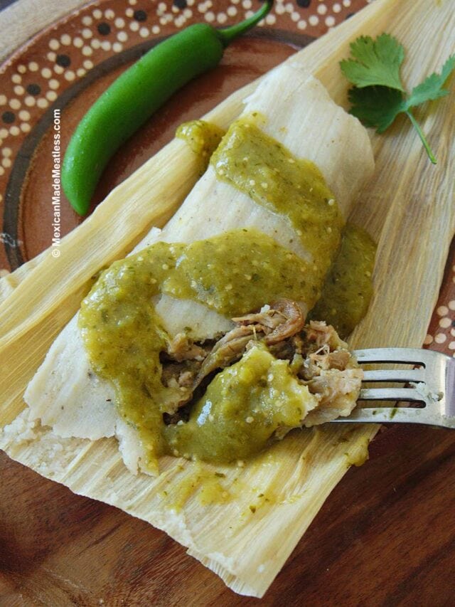 One jackfruit tamale on top of corn husk with green salsa drizzled over it. 