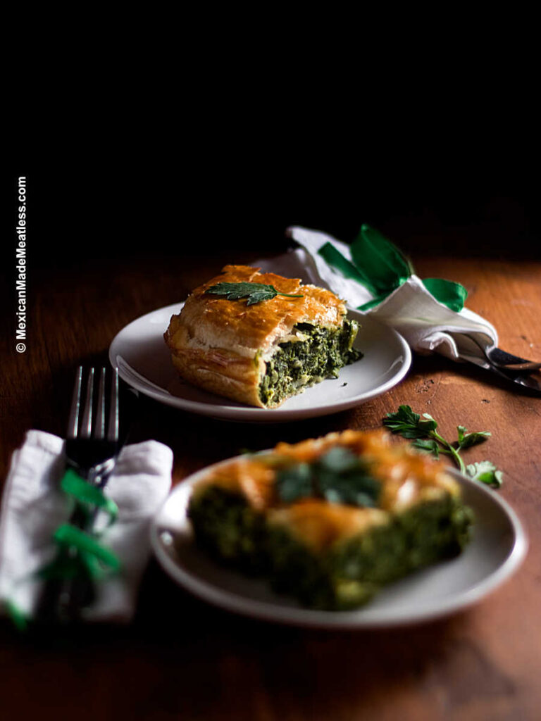 Two white plates with slices of Spanakopita or Greek spinach pie. 