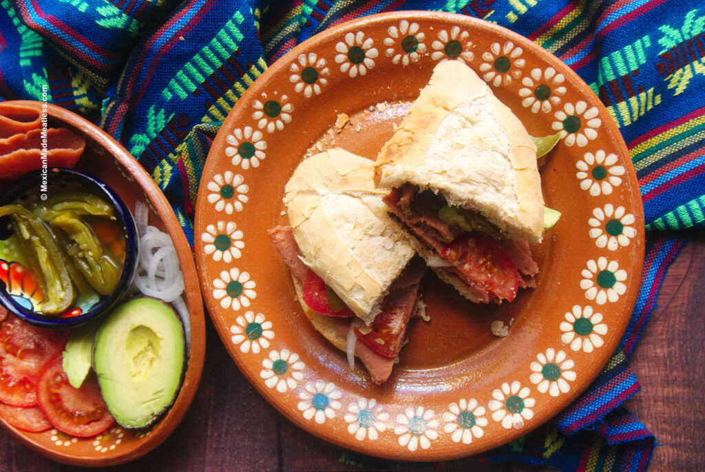 A Mexican ham sandwich or torta de jamón on a traditional Mexican pottery plate.