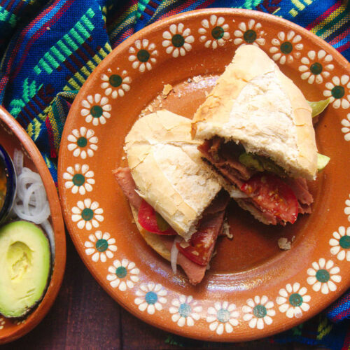 A Mexican ham sandwich or torta de jamón on a traditional Mexican pottery plate.