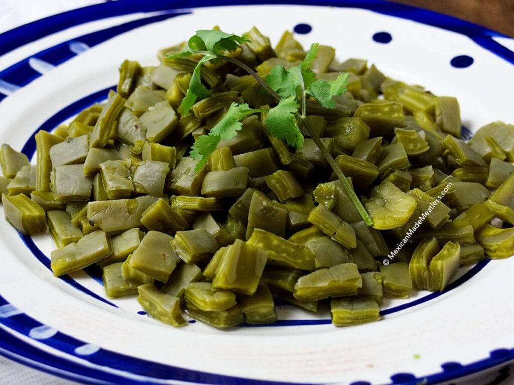 Boiled nopales cactus on a large white and blue plate ready to eat. 