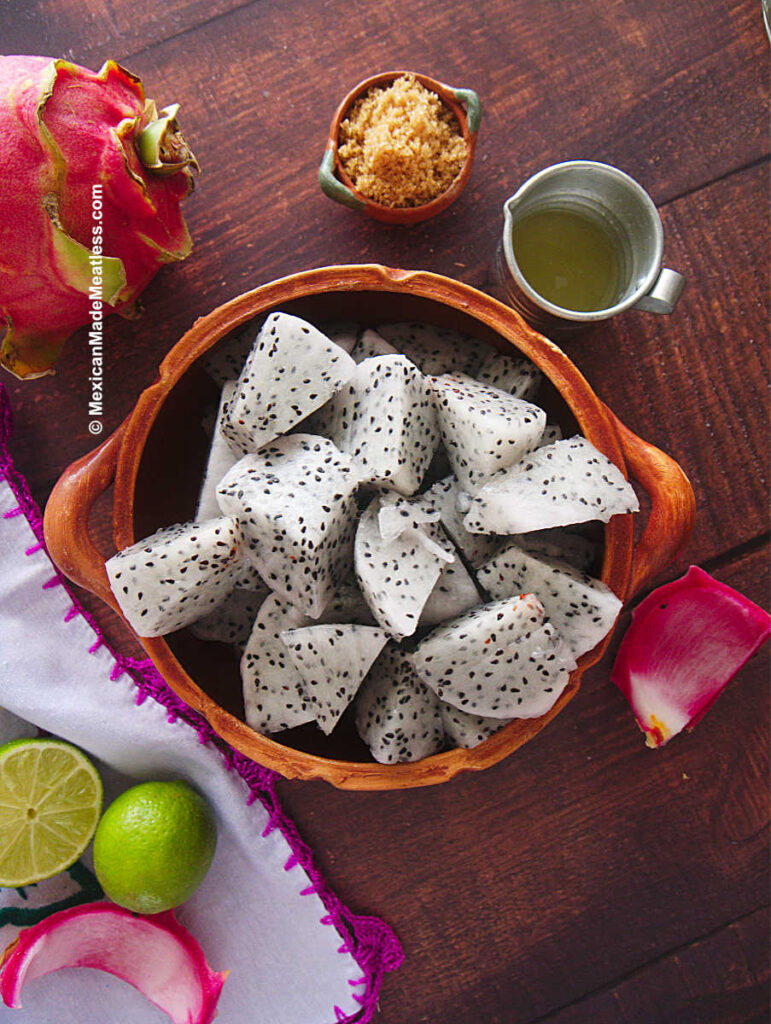 Chopped white dragon fruit with brown sugar and lime juice on a brown table. 