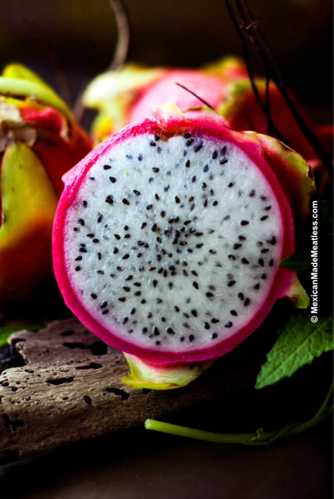 A pink dragon fruit sliced and showing it's white skin. 