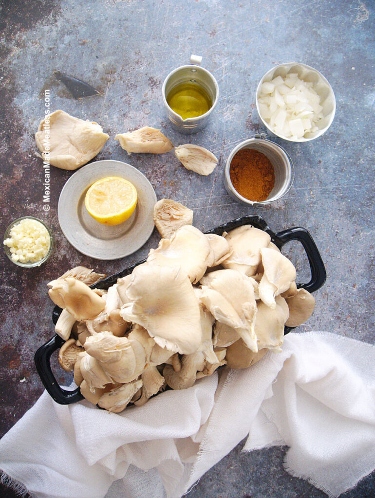 Oyster mushrooms, shawarma seasoning, onion, garlic, olive oil, lemon and salt on a table. Ingredients to make mushroom shawarma wraps. 