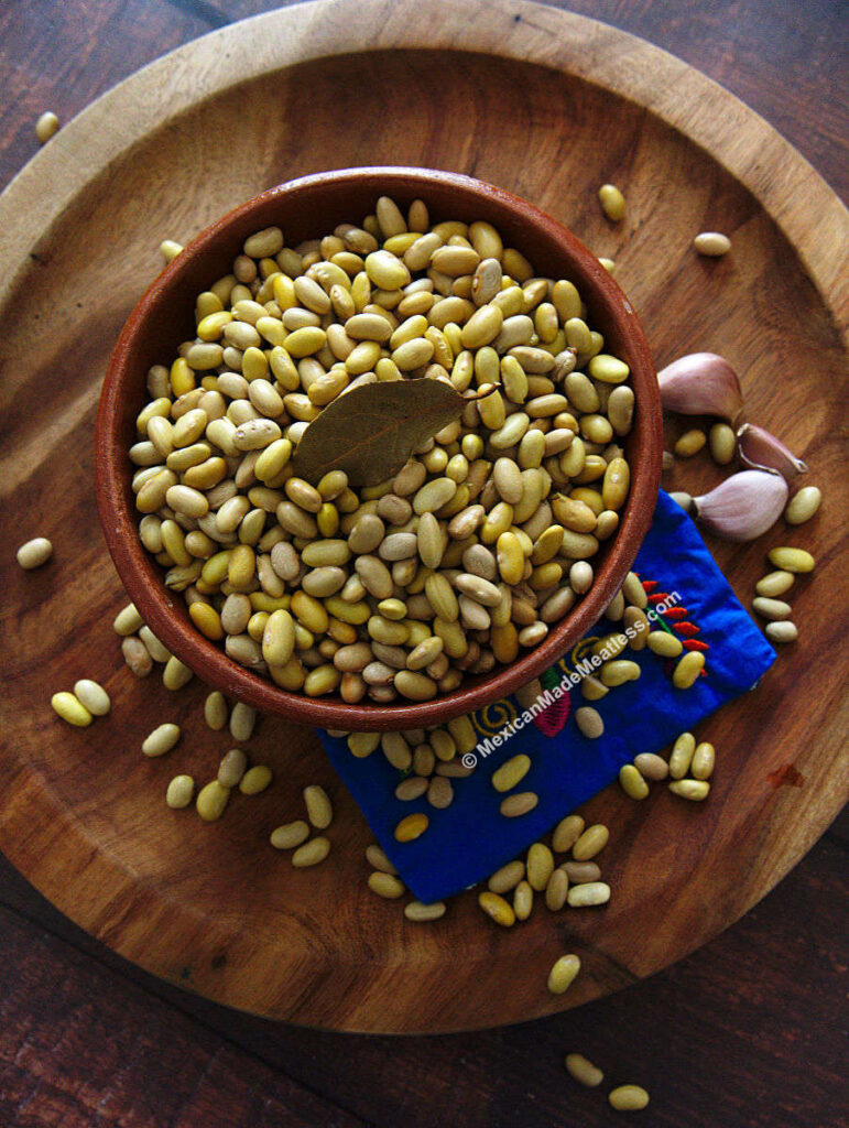 Dried peruvian beans or canary beans inside a small brown bowl.