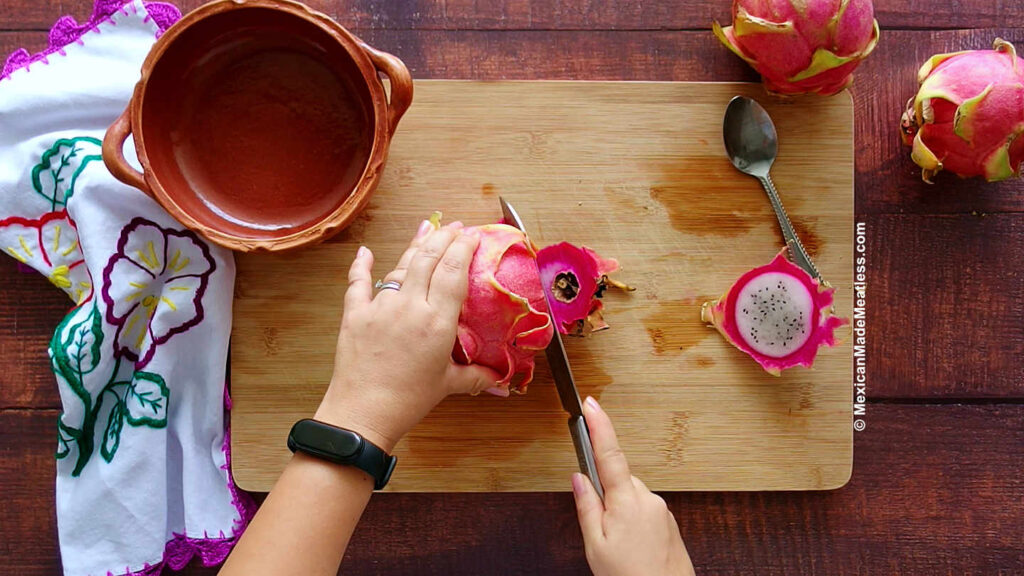 Cutting a pink dragon fruit with a knife.
