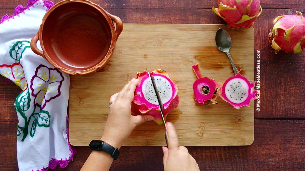Slicing dragon fruit lengthwise with a knife. 
