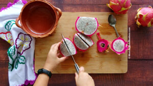 Slicing dragon fruit into wedges with pink peel still on.