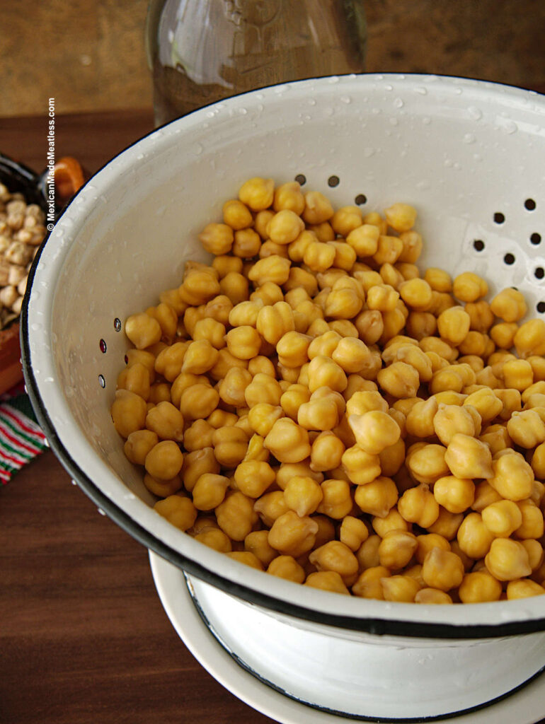 Soaked and rinsed chickpeas inside a white strainer.