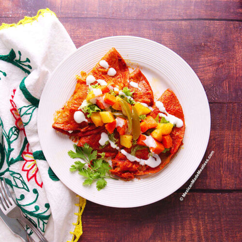 A white plate with red enchiladas made Michoacan style or filled with cheese.