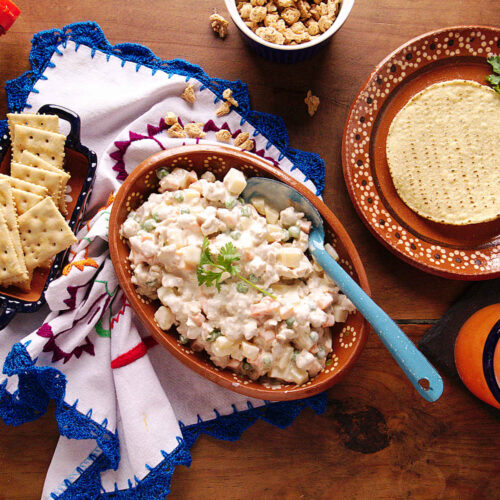 Mexican chicken salad made inside an earthenware bowl with tostada shells and saltine crackers on the side.