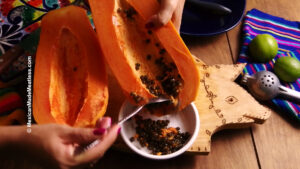 Scraping out the edible seeds from a papaya.