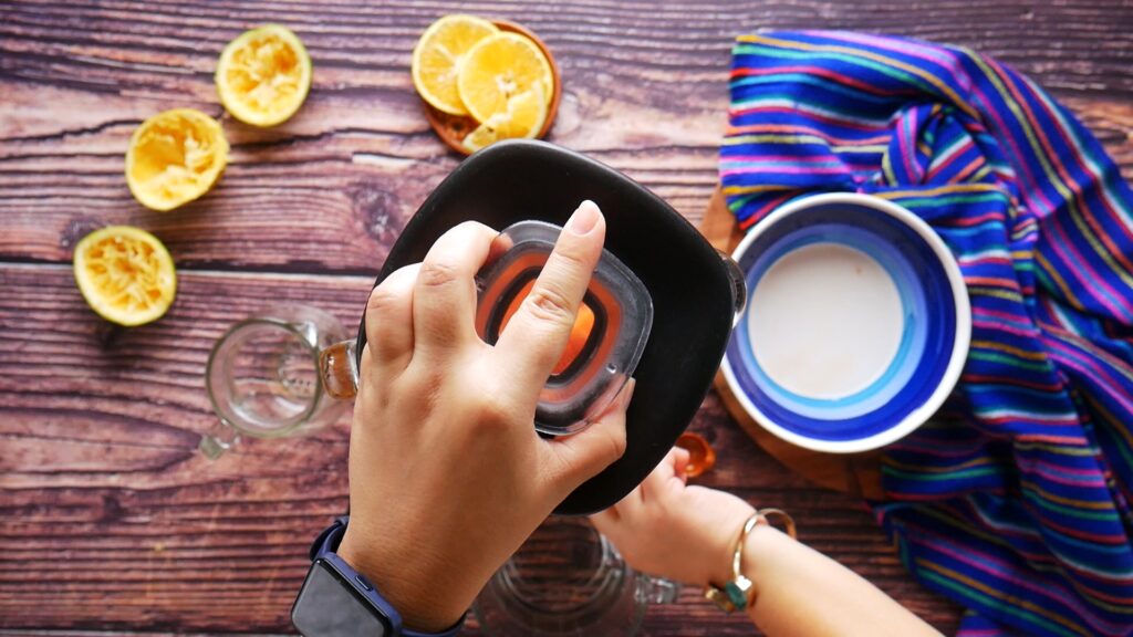 Blending fresh papaya and orange juice in a blender to make agua fresca.