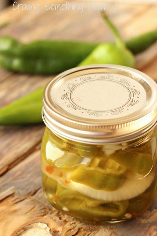 Pickled Hatch chiles and sweet onions inside a small glass jar.