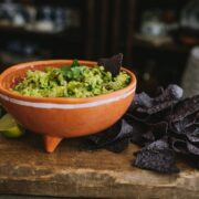 A rustic molcajete filled with Hatch green chile guacamole and corn chips.