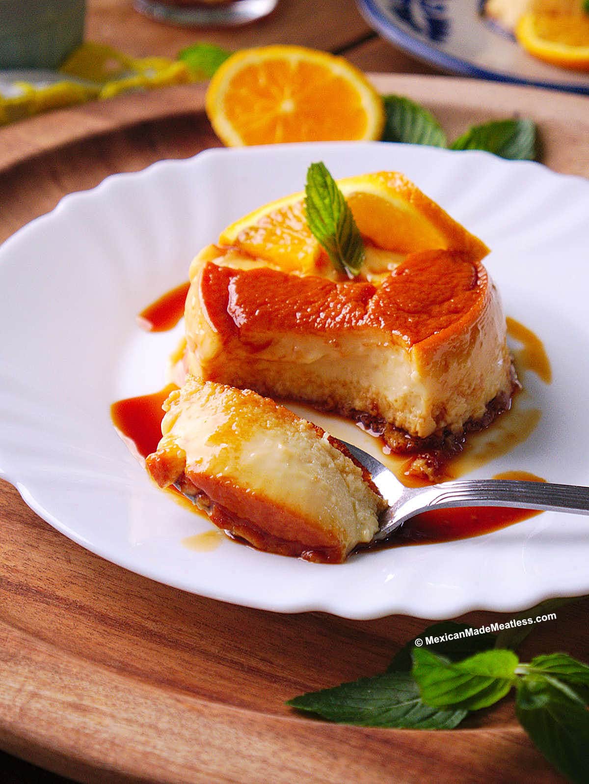 Individual flan made with La Lechera and orange juice served on a small white plate with caramel sauce.