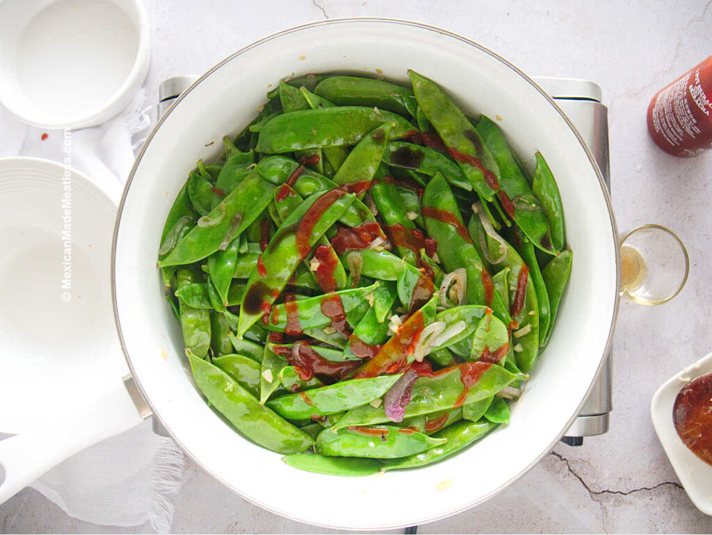 Sauted snow peas drizzled with sriracha hot sauce.