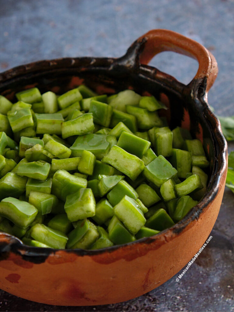 Chopped raw nopales inside a small black and brown bowl.