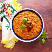 A white and blue bowl filled with Mexican chorizo and beans topped with crispy chorizo and chopped cilantro.