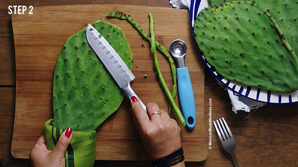 Using a knife on a raw cactus paddle to remove the spines.