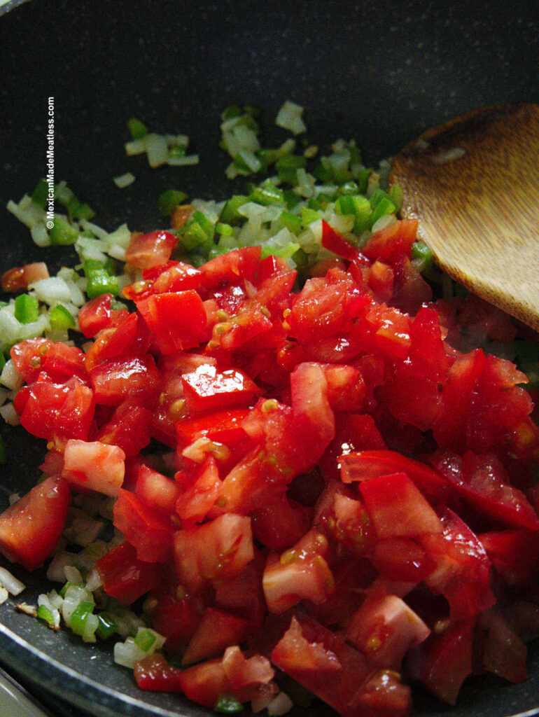 Adding tomatoes to the onion and jalapenos.