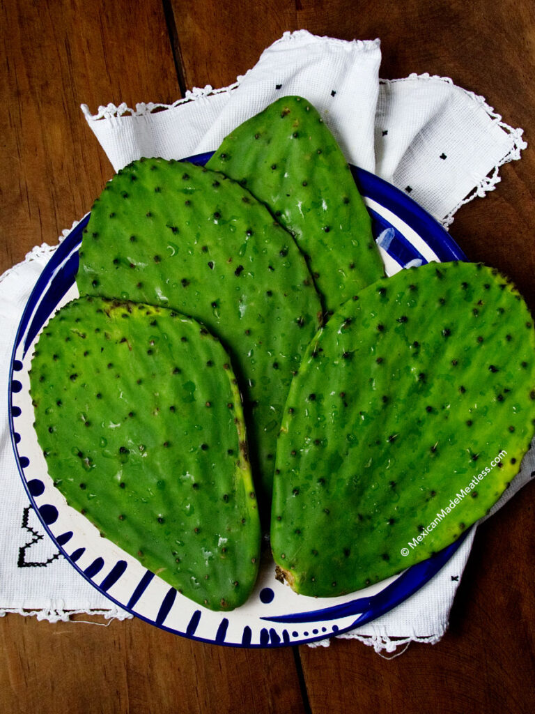 Four raw cactus leaves on a white and blue blue ready to clean and remove their spines. 