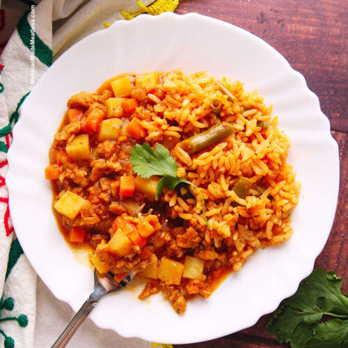 Mexican vegan picadillo served with arroz Mexicano on a white plate.
