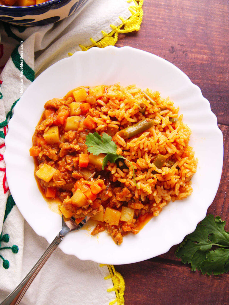 Mexican vegan picadillo served with arroz Mexicano on a white plate.