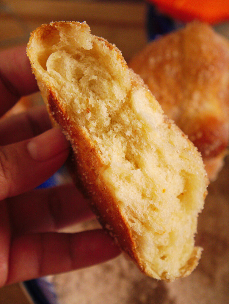 A sliced half of Mexican pan de muerto showing how airy and fluffy it is.