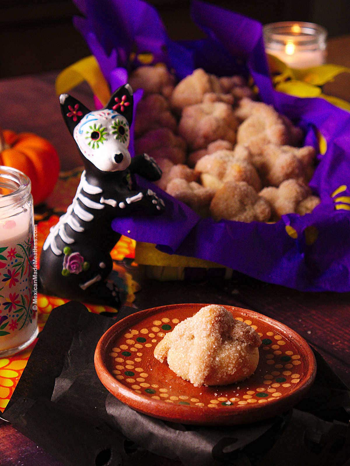 Day of the Dead cookies shaped and flavored just like pan de muerto sitting on a dark table.
